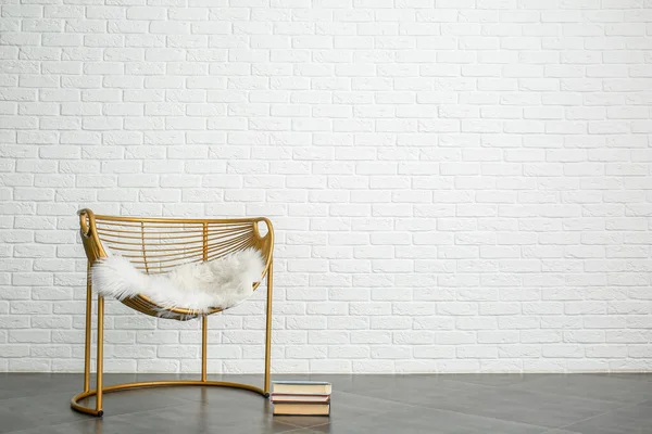 Rahat bir koltuk ve beyaz tuğla duvara yakın kitaplar. — Stok fotoğraf
