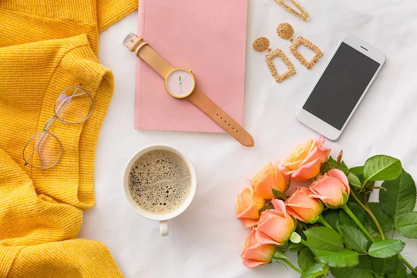 Rose flowers with mobile phone, cup of coffee and female accessories on white background — Stock Photo, Image