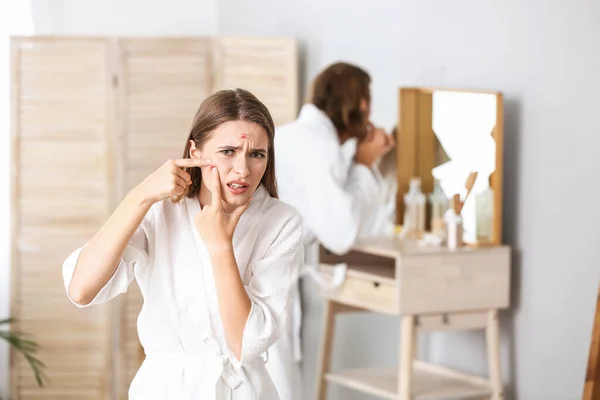 Portrait of young woman with acne problem squishing pimples at home — Stock Photo, Image