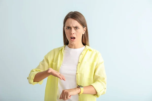 Mujer joven enojado con reloj en el fondo de color —  Fotos de Stock