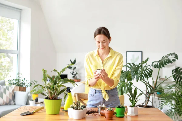 Jovem mulher cuidando de plantas de sala em casa — Fotografia de Stock