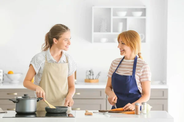 Young woman and her mother cooking together in kitchen — Stock Photo, Image