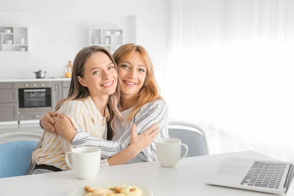 Happy mother and daughter with laptop in kitchen — Stock Photo, Image