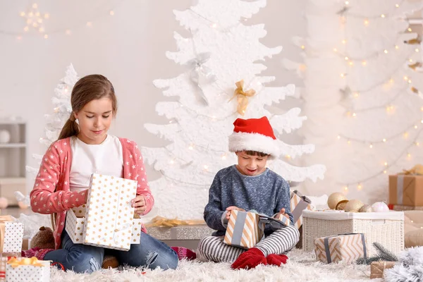 Nettes kleines Mädchen öffnet Weihnachtsgeschenke zu Hause — Stockfoto