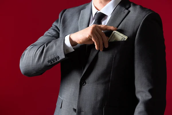 Бизнесмен кладет взятку в карман на цветном фоне. Концепция коррупции — стоковое фото