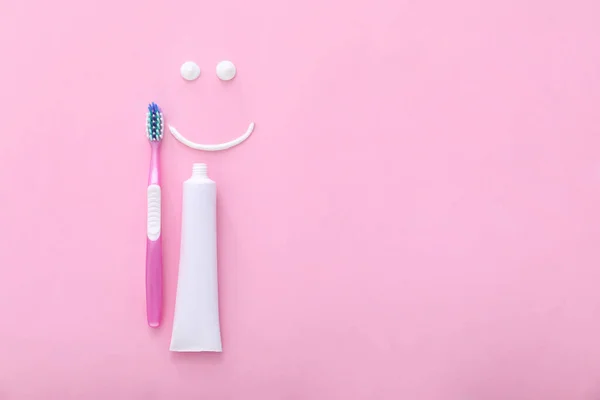 Tooth brush, paste and drawn smile on color background