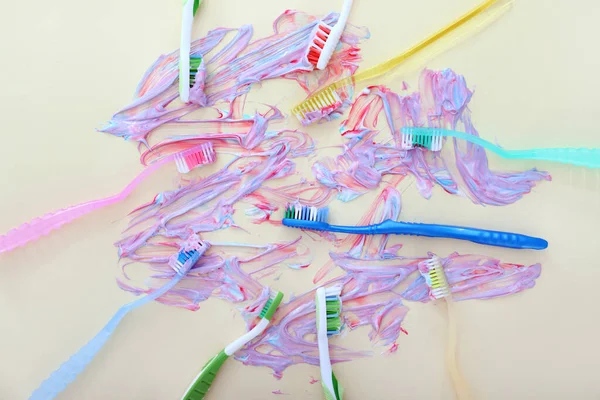 Escovas de dentes e pasta manchada no fundo claro — Fotografia de Stock