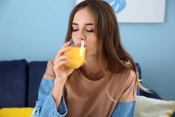 Beautiful young woman drinking orange juice at home — Stock Photo, Image