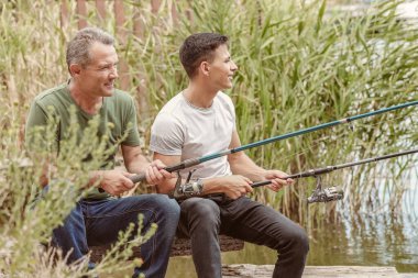 Genç adam ve babası nehirde balık tutuyor.