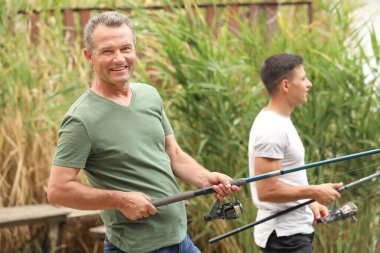 Genç adam ve babası nehirde balık tutuyor.