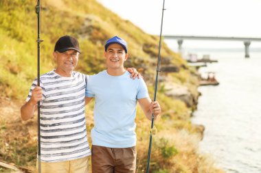 Genç adam ve babası nehirde balık tutuyor.