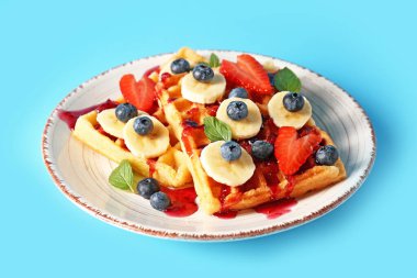 Renkli arkaplanda meyveli lezzetli waffle tabağı ve yabanmersini reçeli