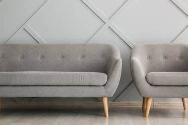 Modern kanepe ve koltuk ışık duvarının yanında.