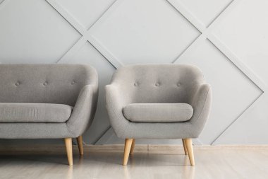 Modern kanepe ve koltuk ışık duvarının yanında.