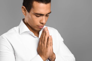 Genç Afrikalı-Amerikalı adam gri arka plan üzerinde dua