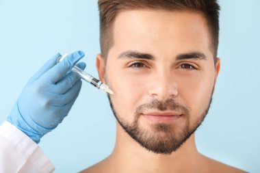 Yakışıklı adam renk arka plan üzerinde dolgu enjeksiyonu alan