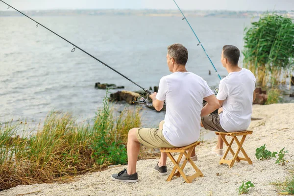 Young man and his father fishing on river — Stock Photo, Image