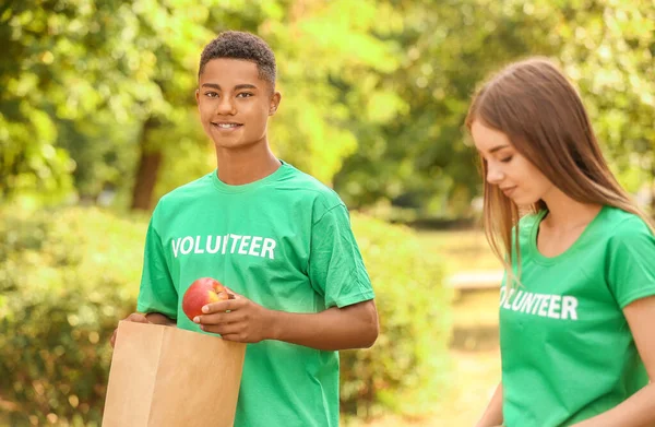 Jóvenes voluntarios con comida para pobres al aire libre — Foto de Stock