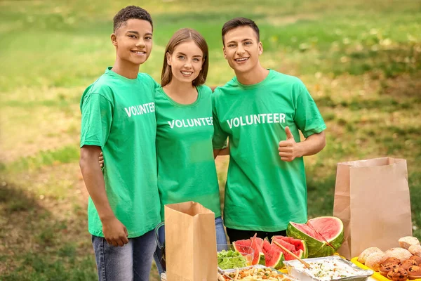 Young volunteers with food for poor people outdoors — Stock Photo, Image