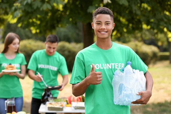 Jóvenes voluntarios afroamericanos con agua para pobres al aire libre — Foto de Stock