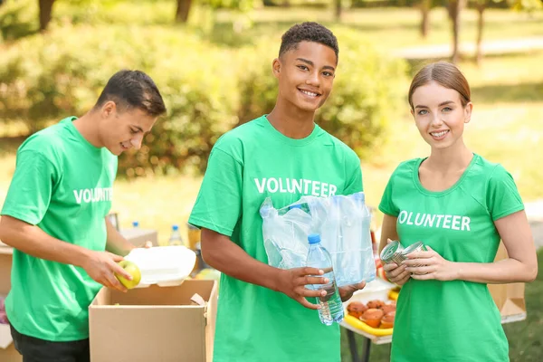 Young volunteers with food for poor people outdoors — Stock Photo, Image