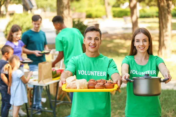 Jóvenes voluntarios con comida para pobres al aire libre — Foto de Stock