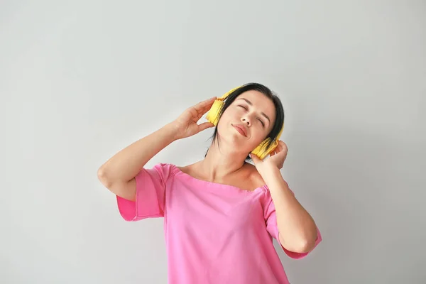 Portret van mooie vrouw luisteren naar muziek op grijze achtergrond — Stockfoto