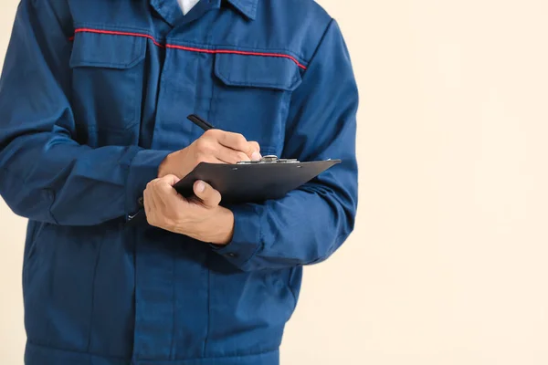 Male car mechanic with clipboard on color background — Stock Photo, Image