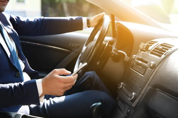 Успішний бізнесмен використовує мобільний телефон під час водіння сучасного автомобіля — стокове фото