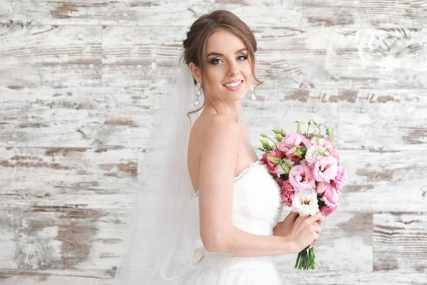 Portret van een mooie jonge bruid met bruidsboeket op houten achtergrond — Stockfoto