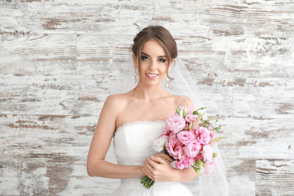 Портрет красивой молодой невесты со свадебным букетом на деревянном фоне
