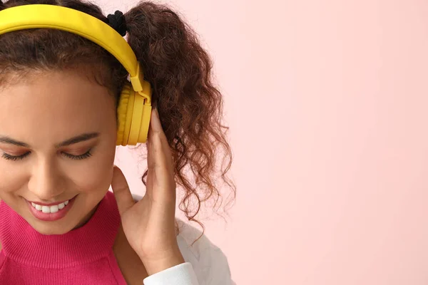 Beautiful African-American woman listening to music on color background — Stock Photo, Image
