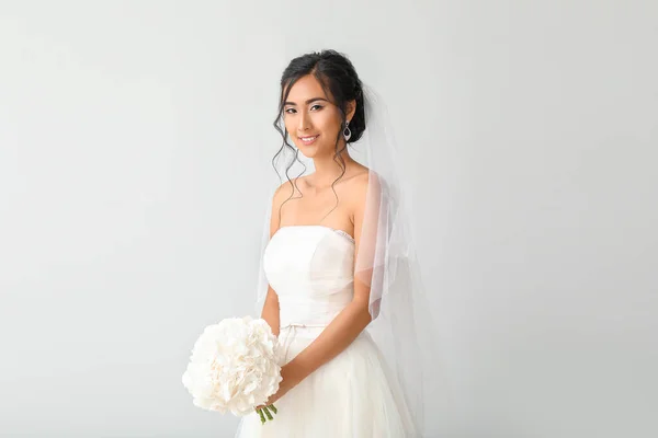 Beautiful young Asian bride on light background — Stock Photo, Image