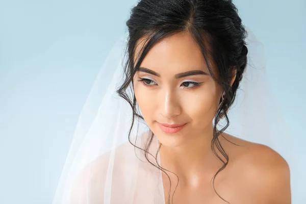 Beautiful young Asian bride on color background — Stock Photo, Image