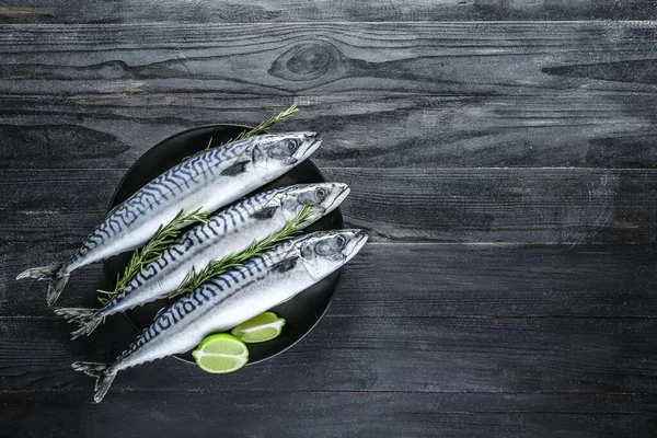 Plate with raw mackerel fish on dark table — Stock Photo, Image