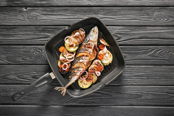 Grill pan with prepared mackerel fish and vegetables on dark table — Stock Photo, Image