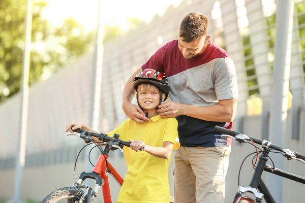 Padre ayudando a su hijo a ponerse el casco de bicicleta al aire libre —  Fotos de Stock