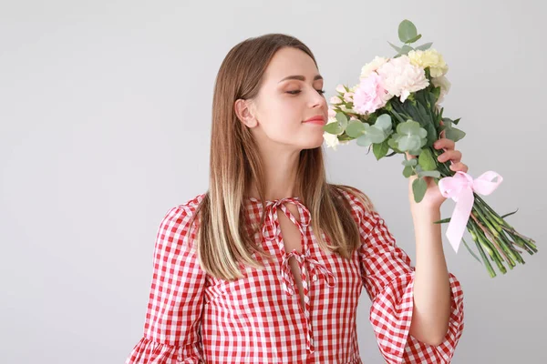 Vacker ung kvinna med bukett av nejlika blommor på ljus bakgrund — Stockfoto