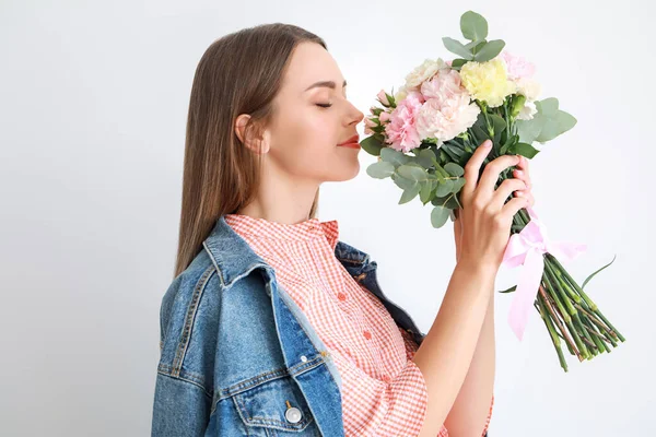 Beautiful young woman with bouquet of carnation flowers on light background — Stock Photo, Image