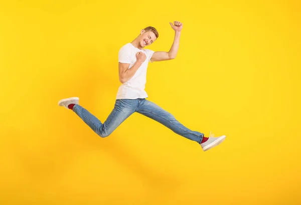 Springender Mann in stylischem T-Shirt auf farbigem Hintergrund — Stockfoto