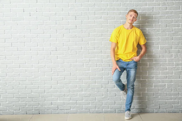 Hombre joven en elegante camiseta cerca de la pared de ladrillo — Foto de Stock