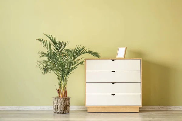 Stylish chest of drawers with houseplant in pot near color wall in room — Stock Photo, Image