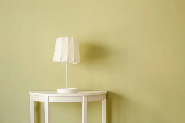 Elegante mesa con lámpara cerca de la pared de color en la habitación — Foto de Stock