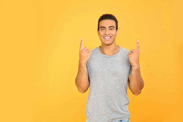 Knappe Afro-Amerikaanse man wijst op iets op kleur achtergrond — Stockfoto