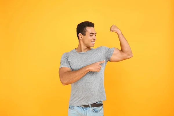 Knappe Afro-Amerikaanse man toont spieren op kleur achtergrond — Stockfoto