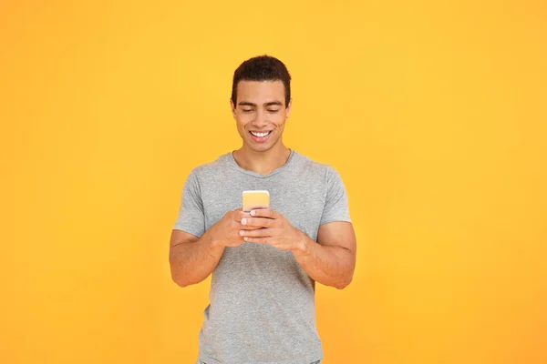 Bonito homem afro-americano com telefone celular no fundo de cor — Fotografia de Stock