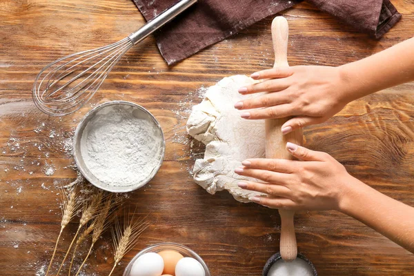Woman rolling out dough on wooden background — ストック写真