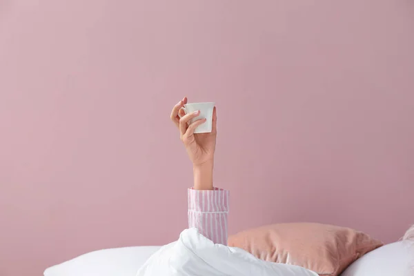 Giovane donna con tazza di caffè sdraiata a letto — Foto Stock