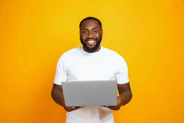 Hombre afroamericano guapo con portátil sobre fondo de color — Foto de Stock