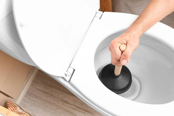 Man using plunger to unclog a toilet bowl — Stock Photo, Image